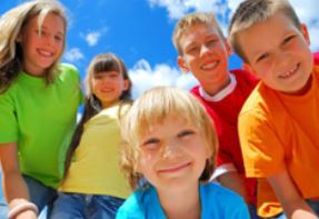 Softfallguys National Softfallguys National Group of five smiling children posing outdoors on a sunny day with a bright blue sky.